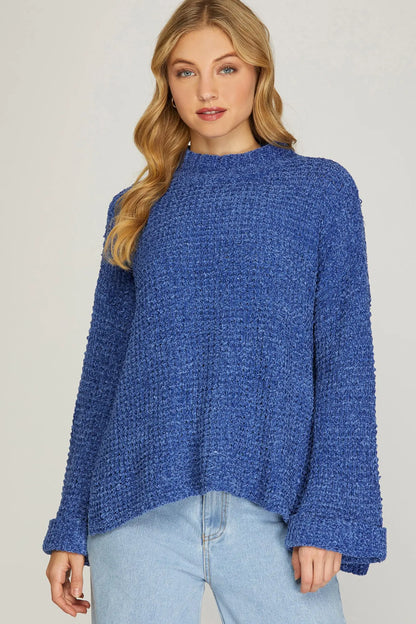 Woman wearing a blue knitted sweater against a plain background