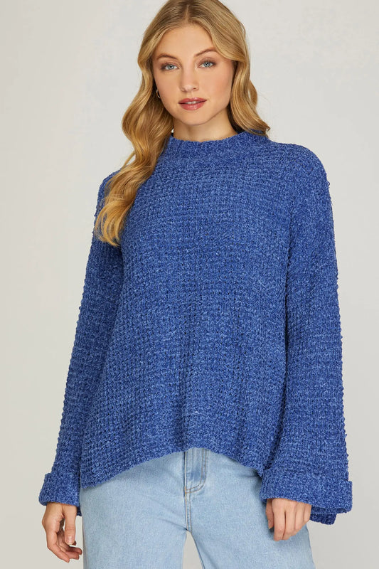 Woman wearing a blue knitted sweater against a plain background
