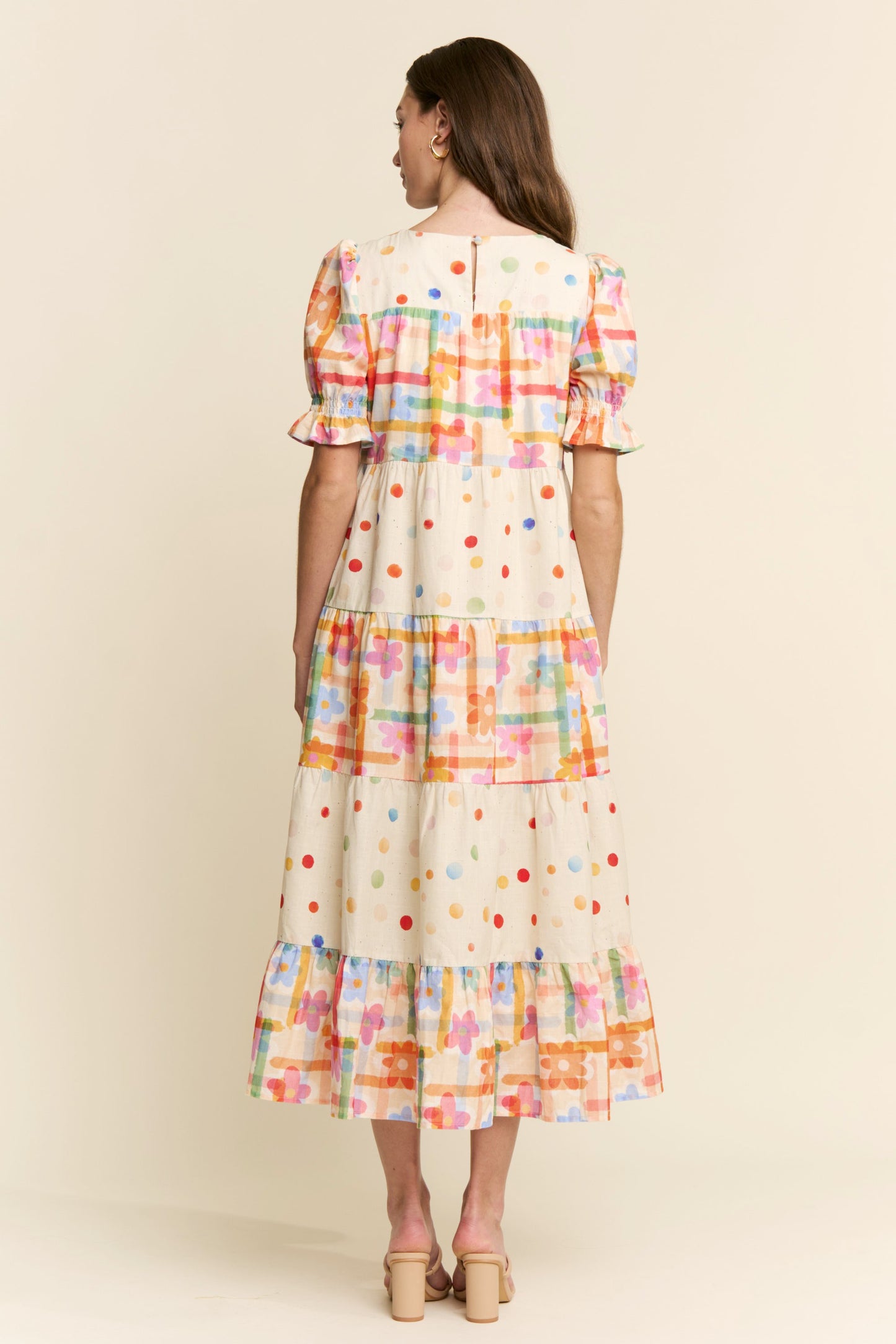 Woman wearing a colorful plaid dress against a beige background