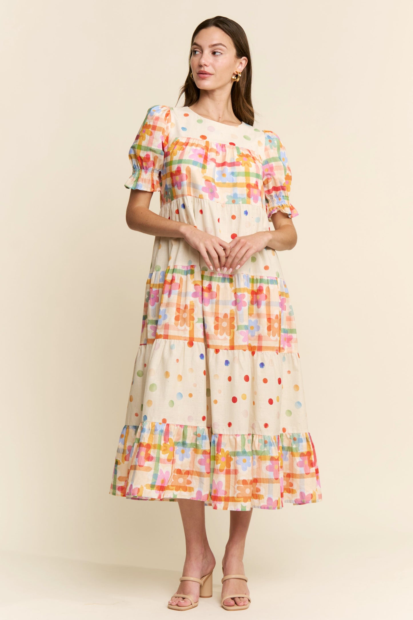 Woman wearing a colorful checkered dress against a plain background