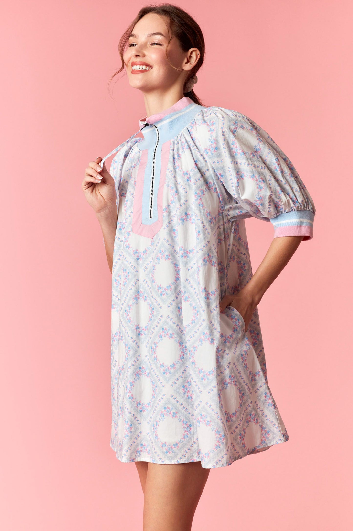 Woman wearing a patterned dress with a pink background