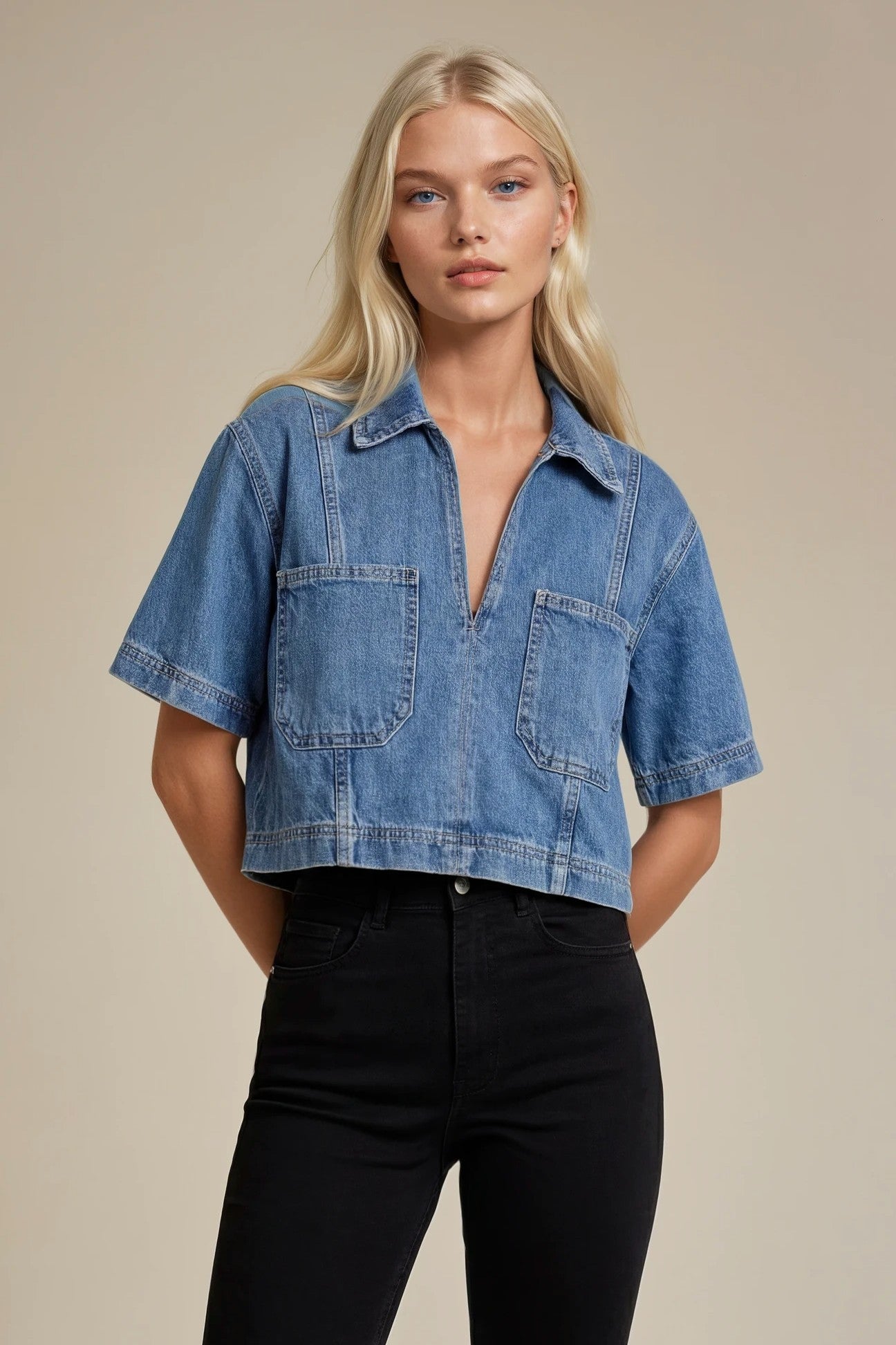Woman wearing a blue denim shirt and black pants against a beige background