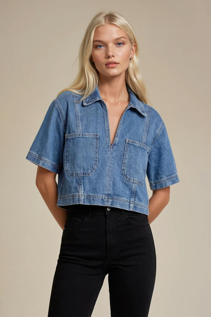 Woman wearing a blue denim shirt and black pants against a beige background