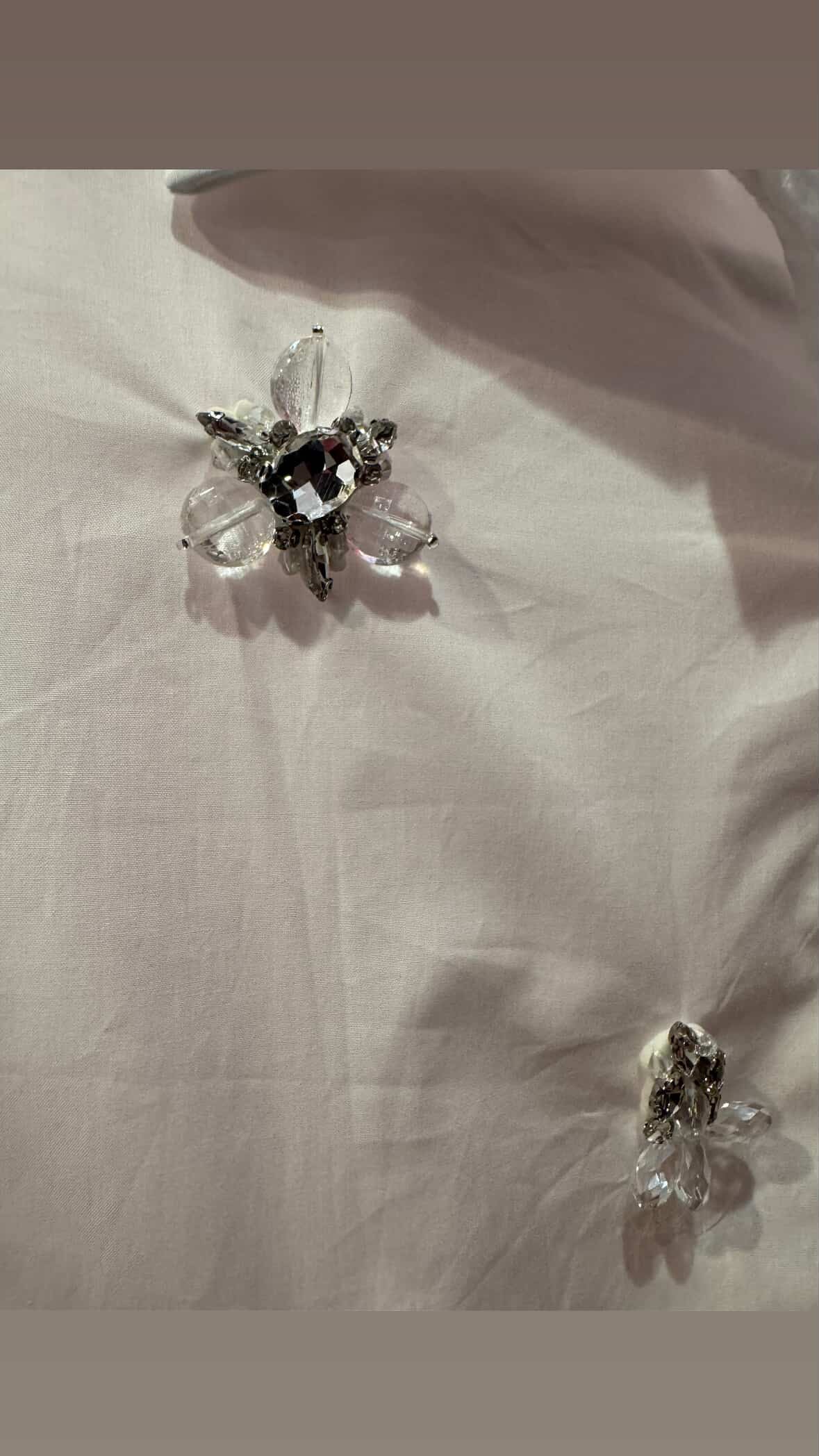 Close-up view of jeweled embellishments on white button-down blouse, showing crystal and bead floral designs from Milo & Lily Boutique.