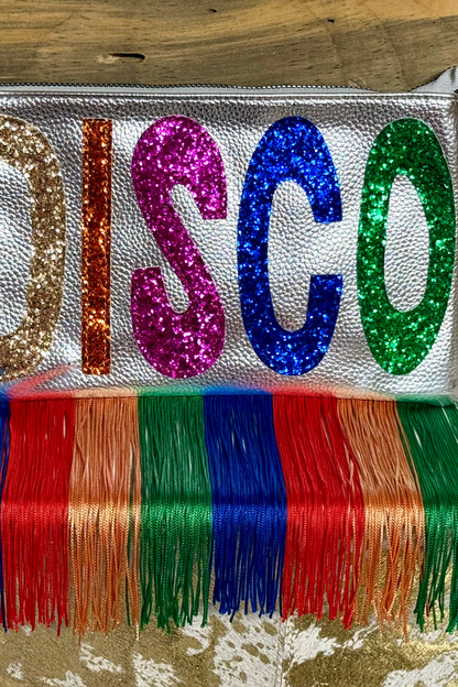 Silver clutch with 'DISCO' in colorful sequins and fringes on a wooden surface