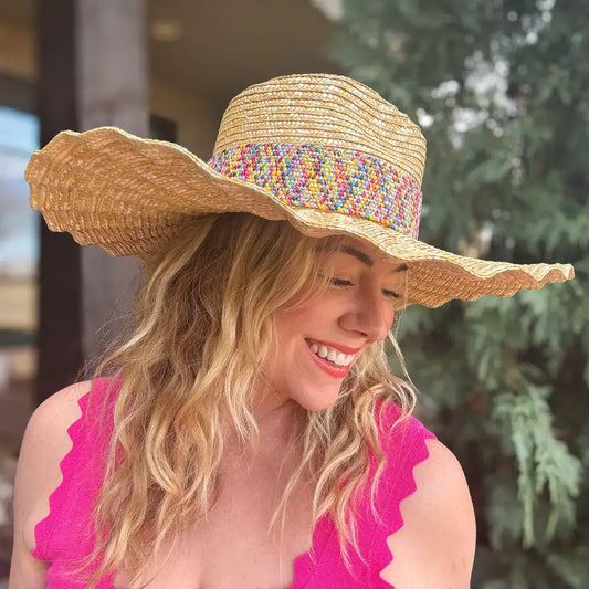 Woman in a pink top wearing a wide-brimmed straw sun hat with colorful band outdoors