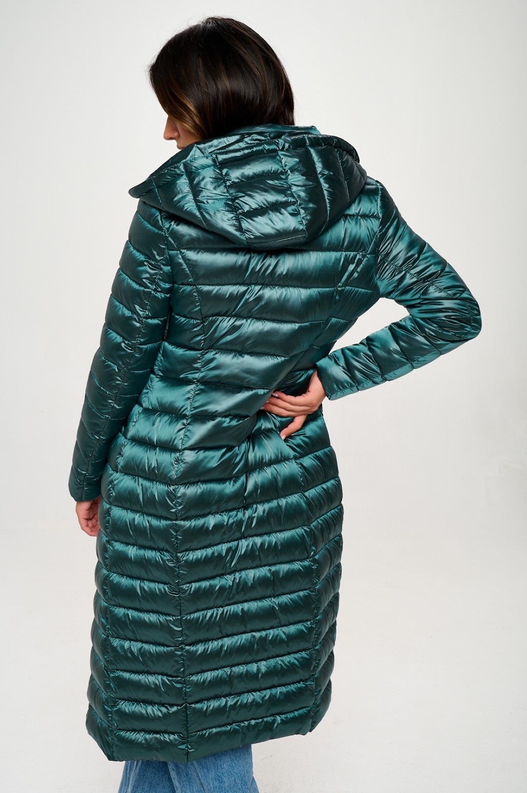 Person wearing a long green puffer coat on a white background