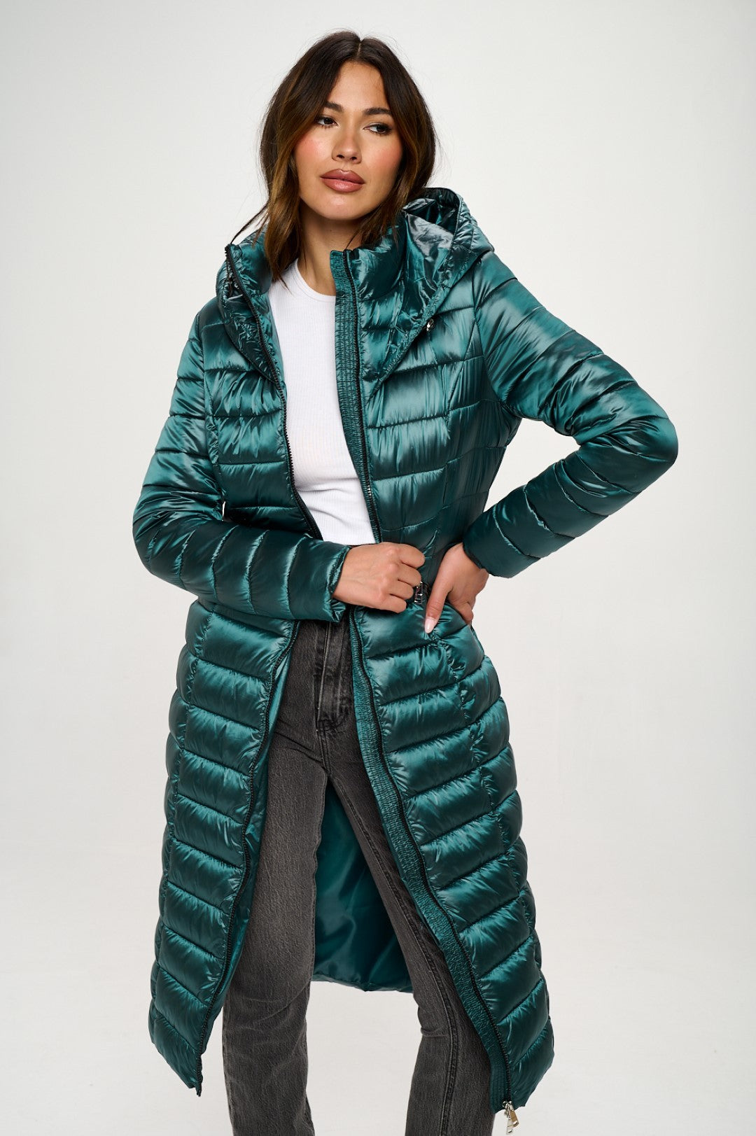 Woman wearing a long teal puffer coat on a white background