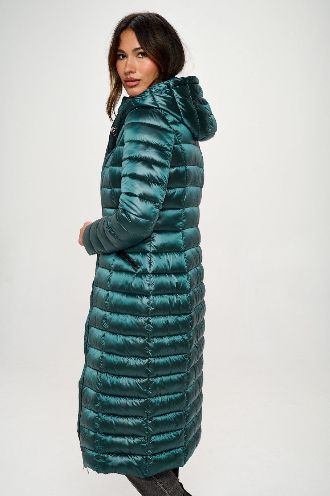 Woman wearing a long teal puffer coat on a white background