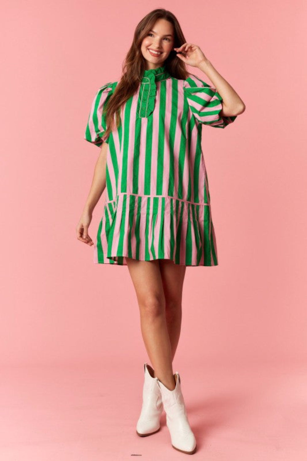 Woman wearing a green and white striped dress on a pink background