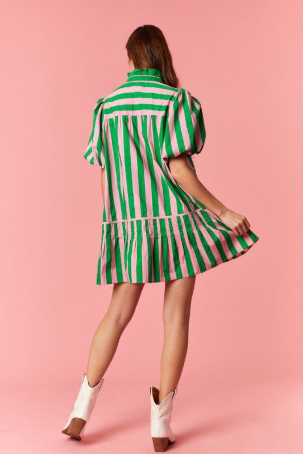 Woman wearing a green and pink striped dress on a pink background