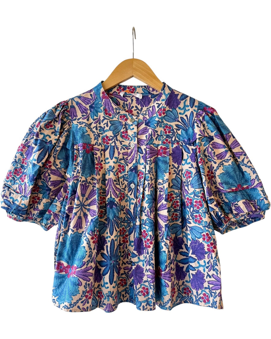 Floral puff sleeve blouse in cobalt blue, lilac, and pink hues displayed on hanger, showing embroidered-style pattern and button front from Milo & Lily Boutique.