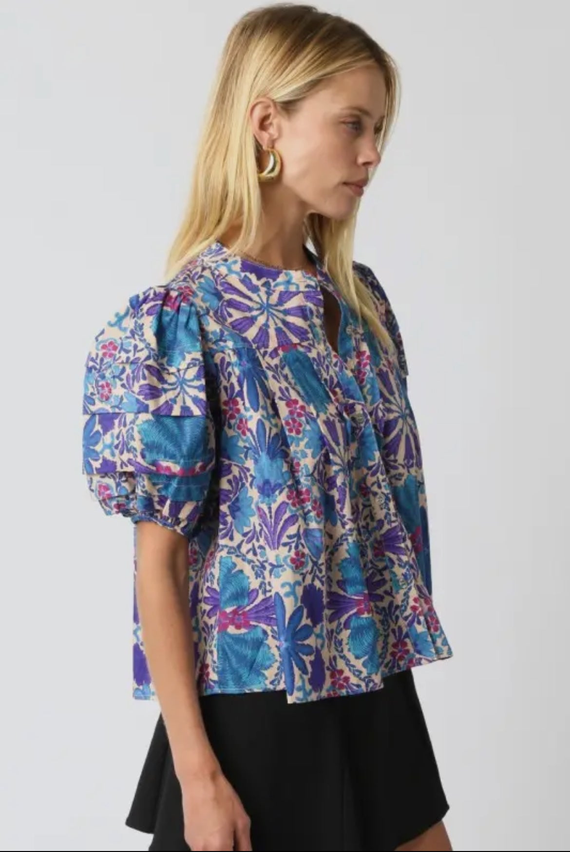 Side view of the puff sleeve floral print blouse in blue, purple, and pink tones with a relaxed fit and gathered detailing on sleeves from Milo & Lily Boutique.