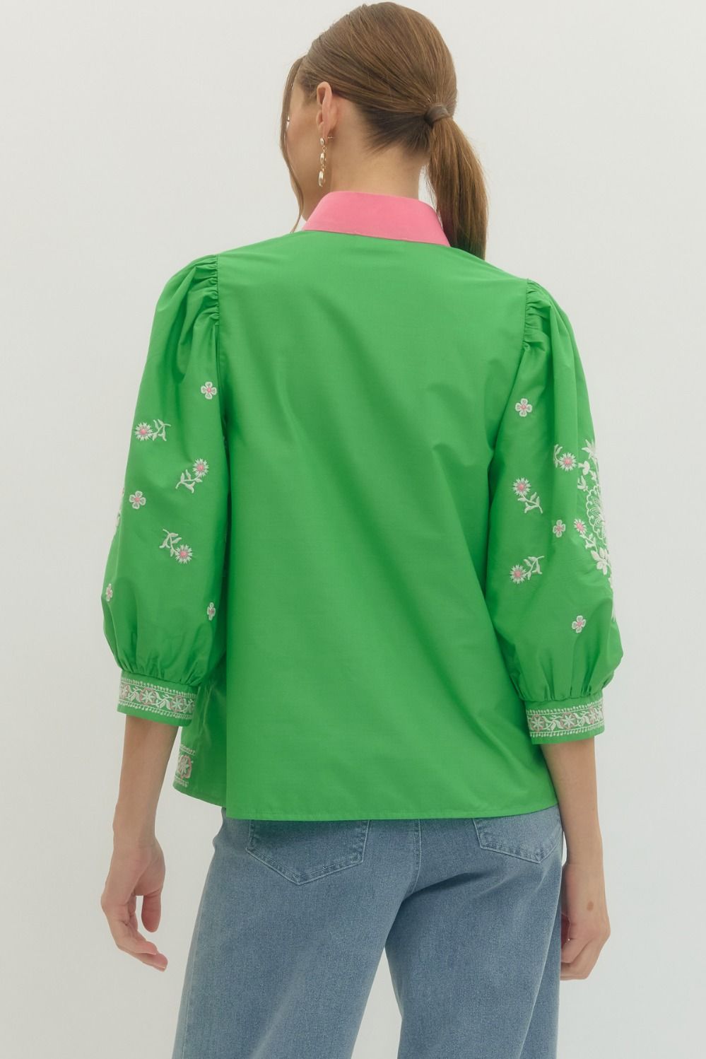 Green embroidered blouse worn by a person on a white background