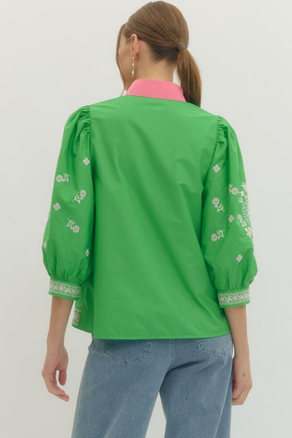 Green embroidered blouse worn by a person on a white background