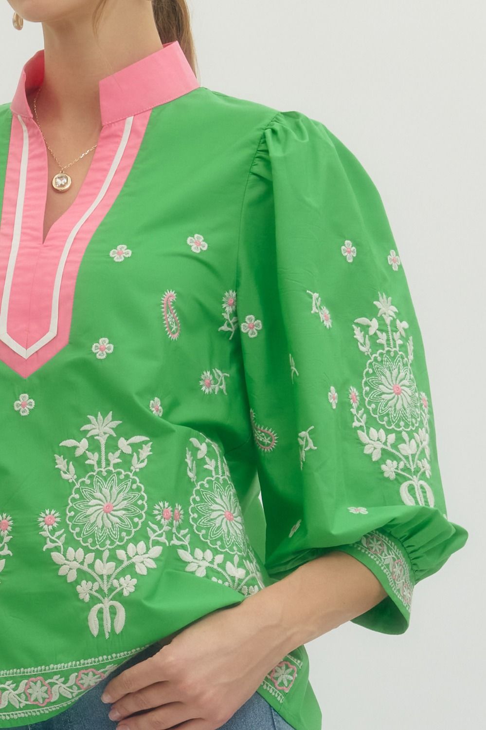 Green embroidered blouse with pink collar on a plain background
