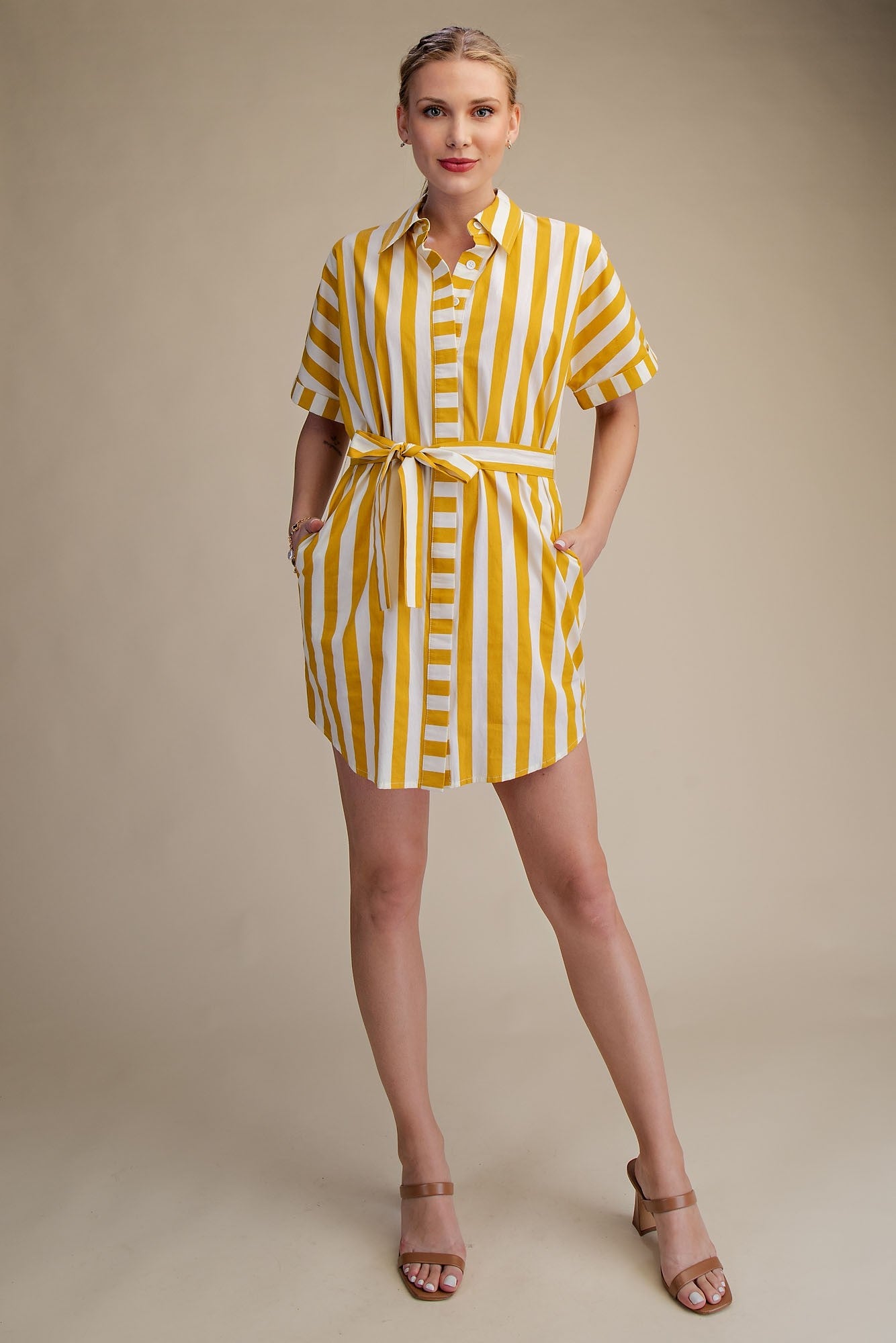 Woman wearing a yellow and white striped dress on a beige background