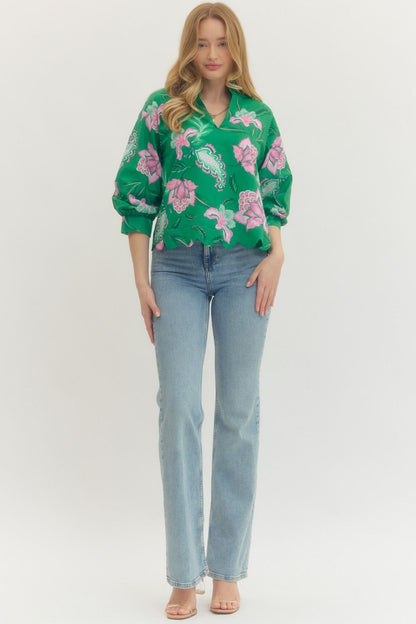 Woman wearing a green floral blouse and blue jeans on a white background