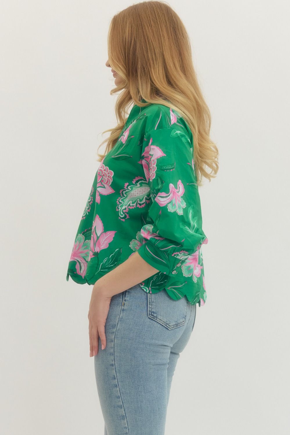Woman wearing a green floral blouse and blue jeans on a white background
