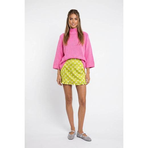 Full-length front view of hibiscus pink mock-neck batwing sweater styled with a lime polka-dot skirt.