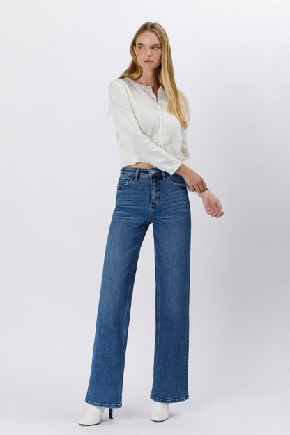 Model wearing high-rise straight leg blue jeans with a clean hem and classic fit — timeless denim from Milo & Lily Boutique styled with a white sweater and boots.