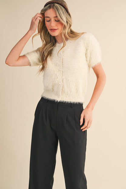 Ivory fuzzy sweater top with pearl buttons styled with black trousers and headband