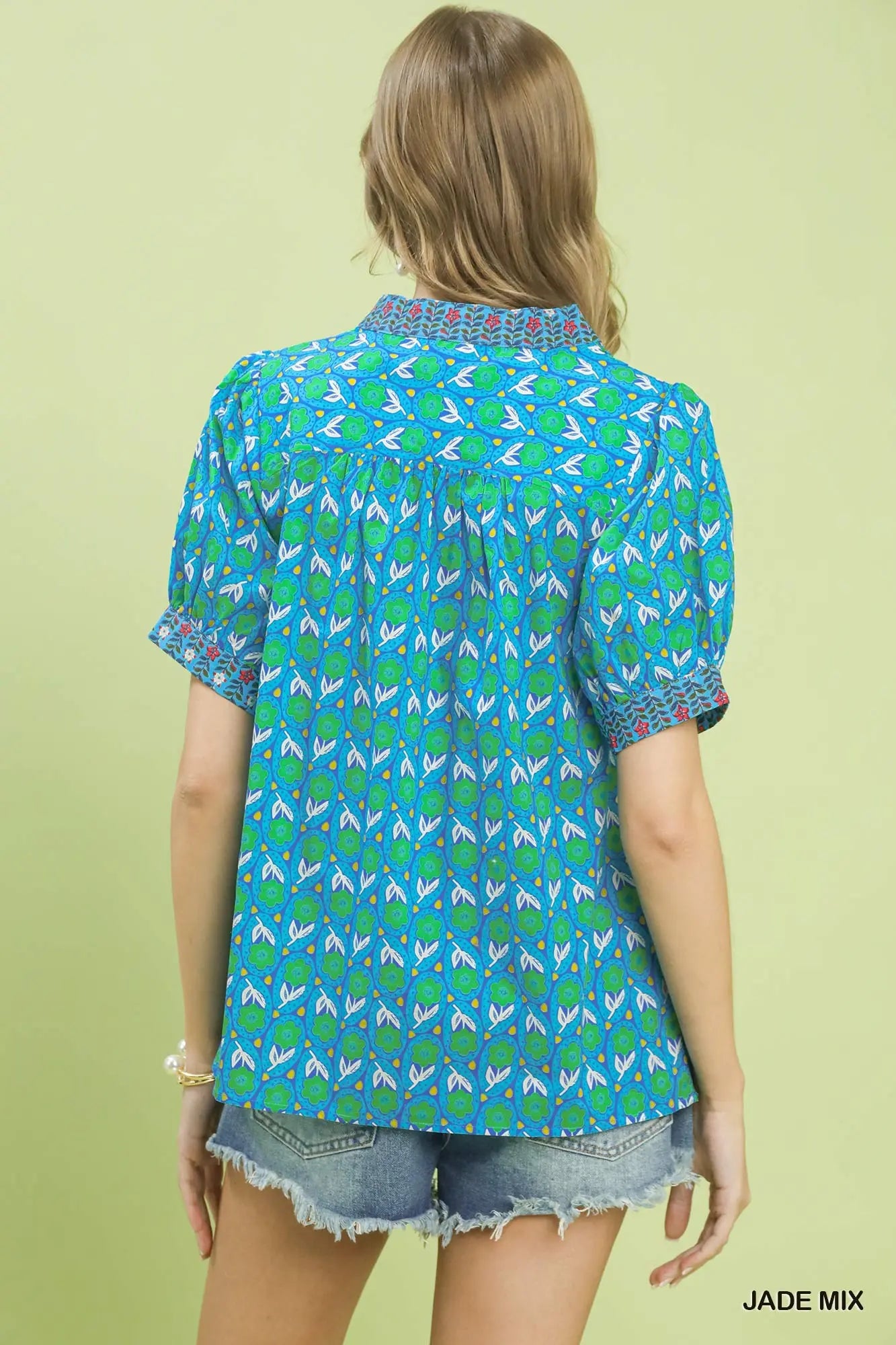 Woman wearing a blue patterned shirt with a green background