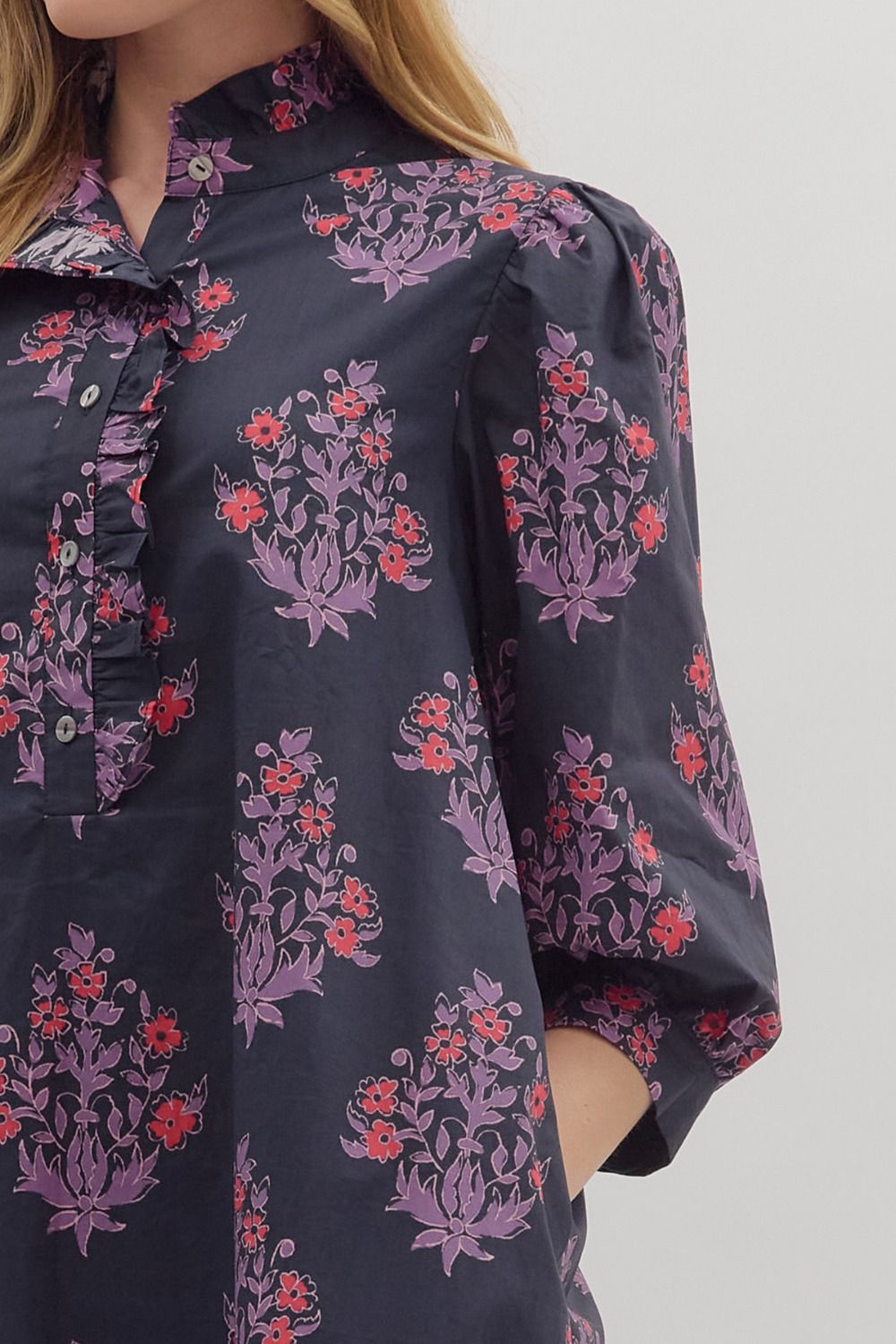 Close-up of ruffled neckline and red-and-lilac floral pattern