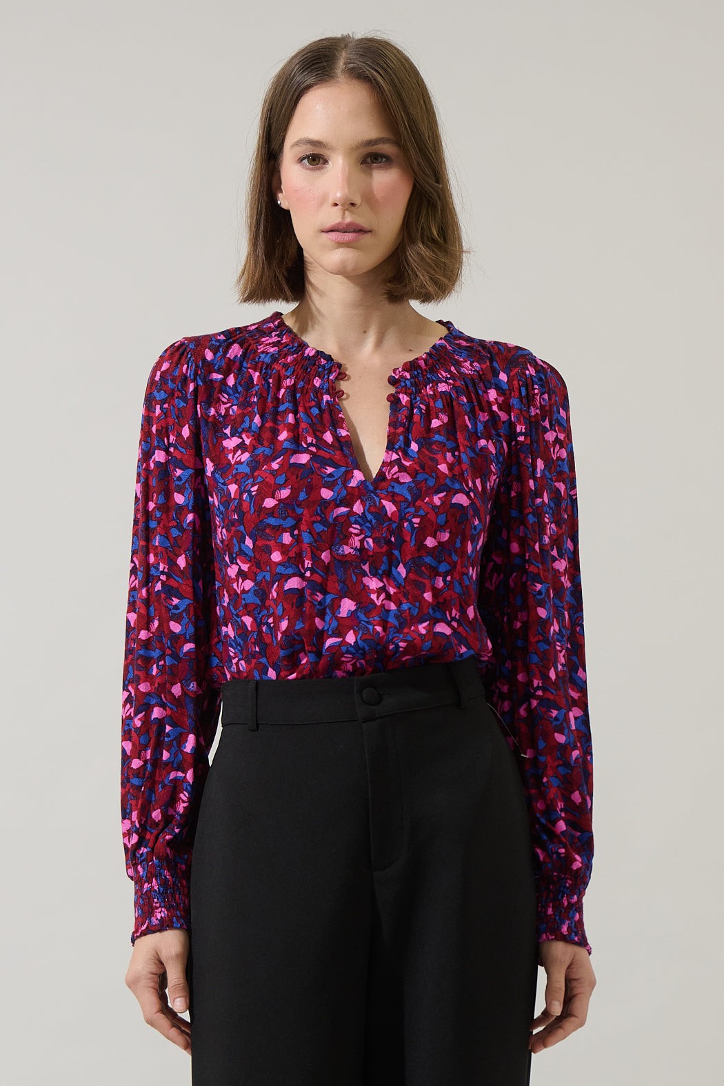 Front view of berry floral print blouse with ruffled neckline and smocked cuffs