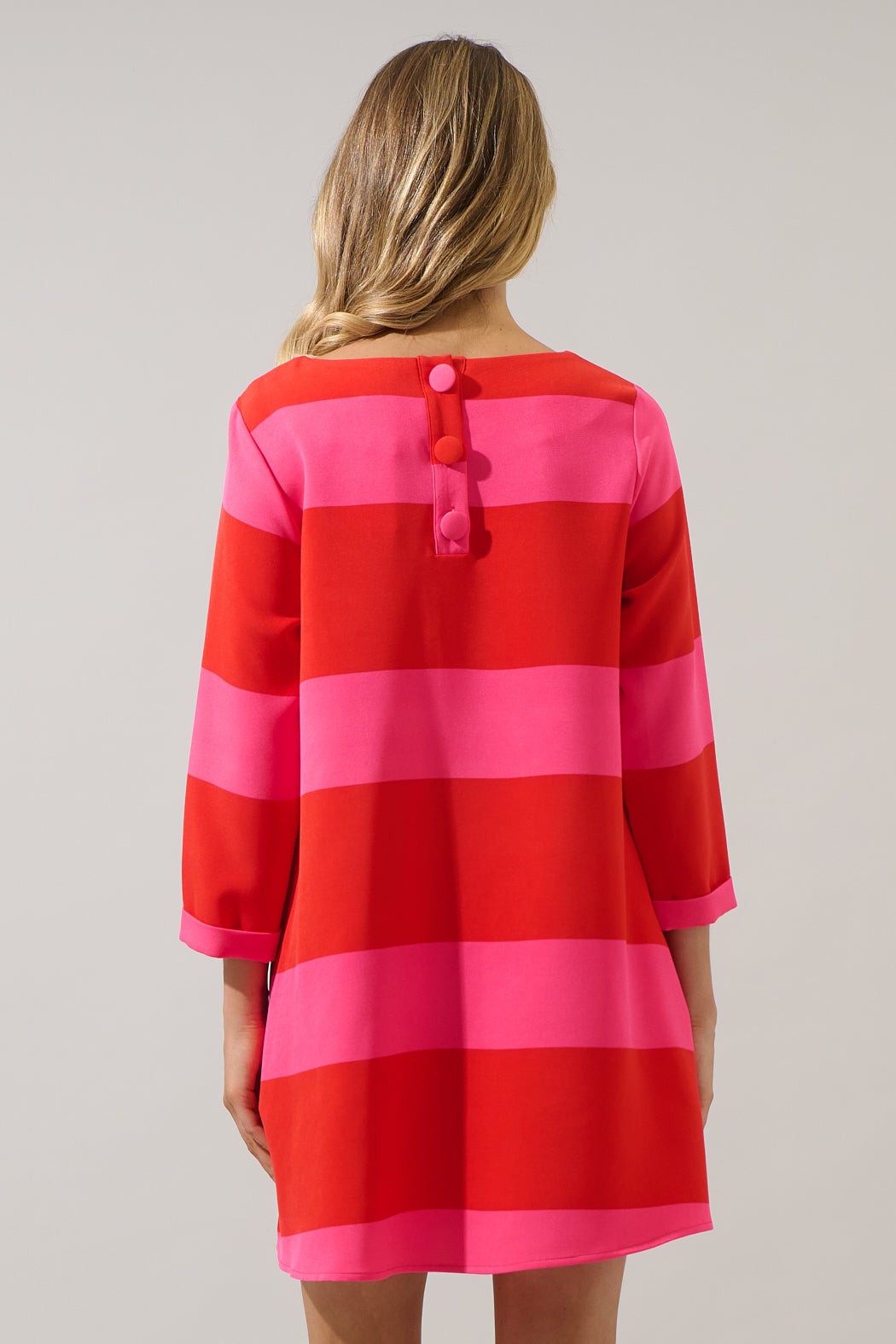Back view of red and pink striped shift dress with button detail