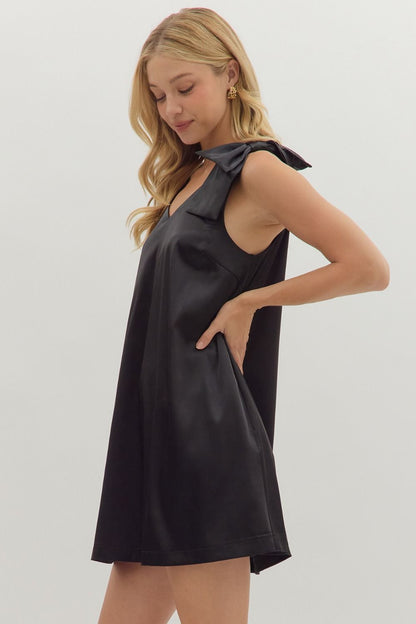 Side view of sleeveless black A-line satin dress with feminine bows