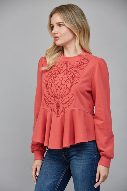 Side view of coral peplum blouse with tonal floral stitching