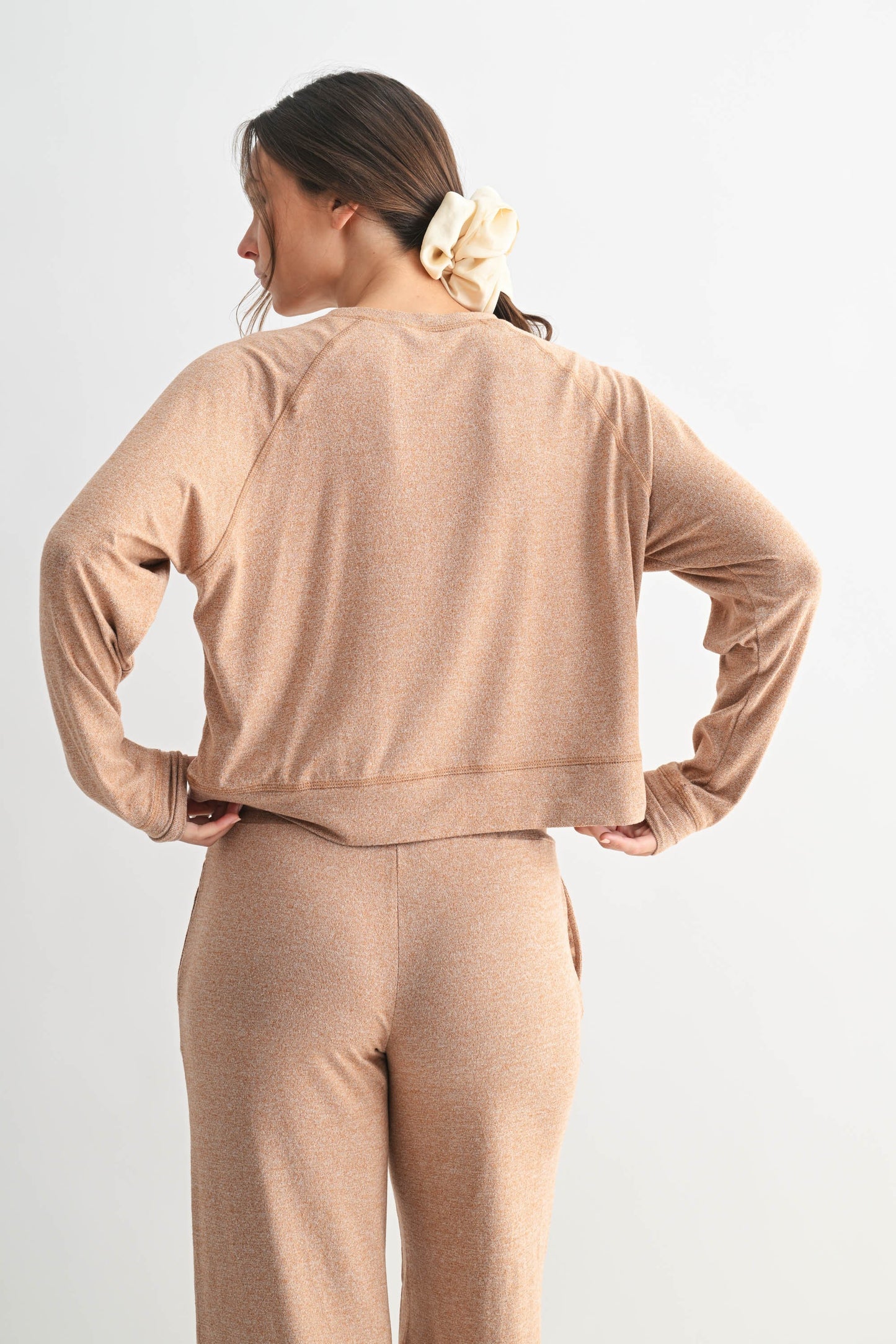 Woman wearing a beige tracksuit against a white background