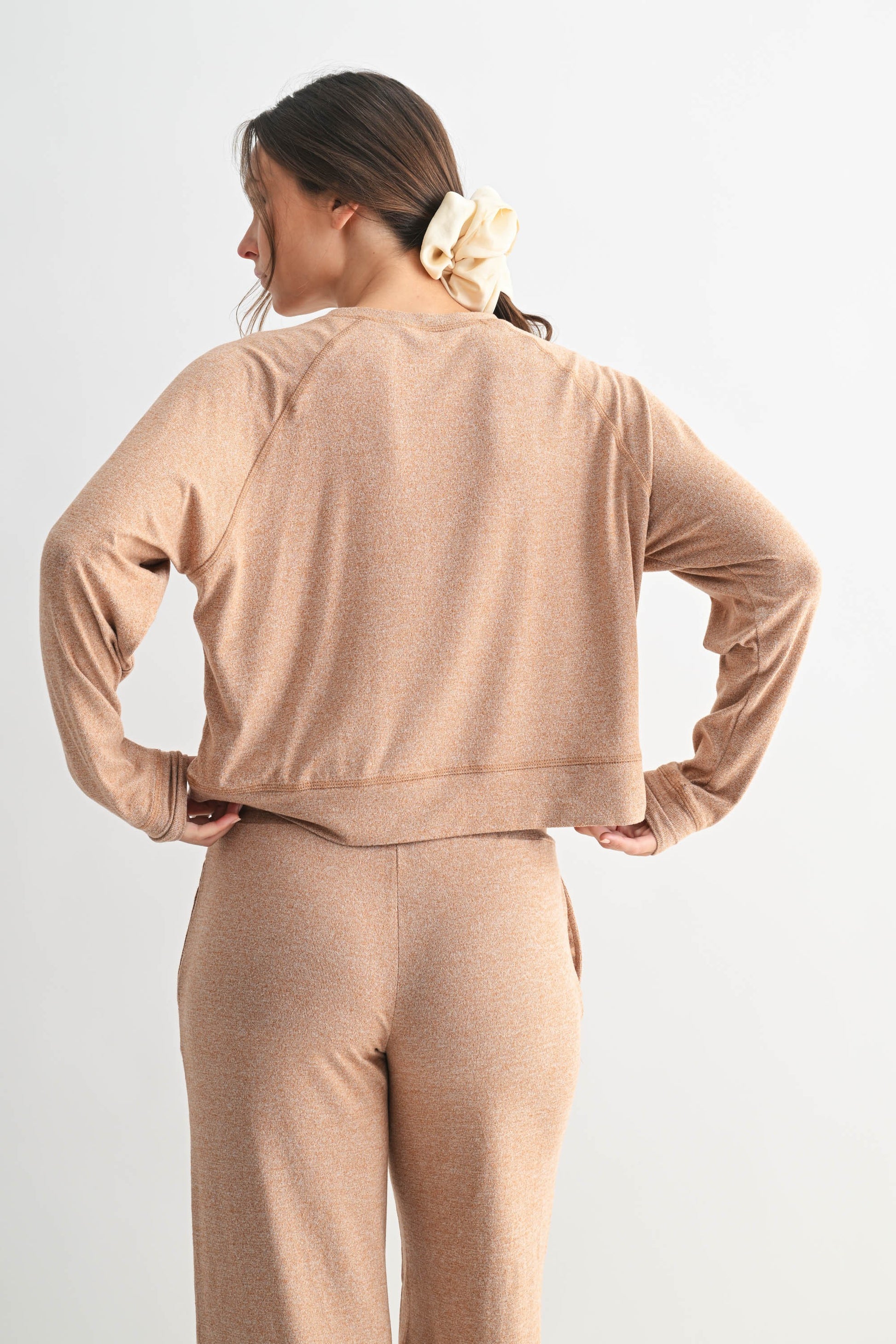 Woman wearing a beige tracksuit against a white background