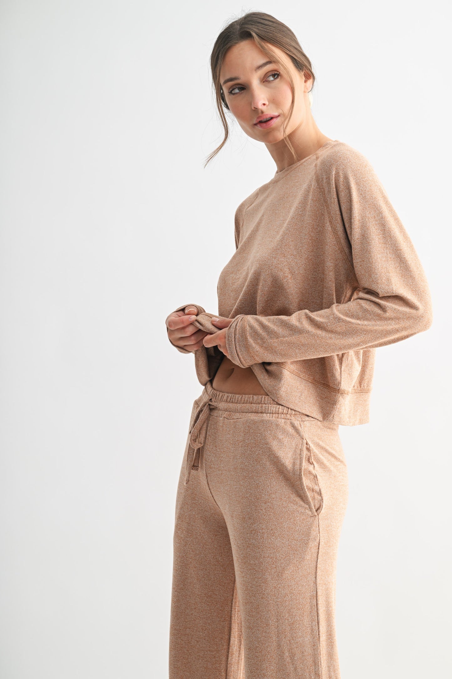 Woman wearing a beige long-sleeve top and pants on a white background