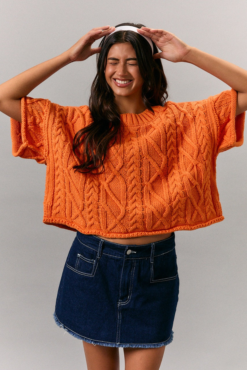 Bright orange cropped cable knit short sleeve sweater front view on model