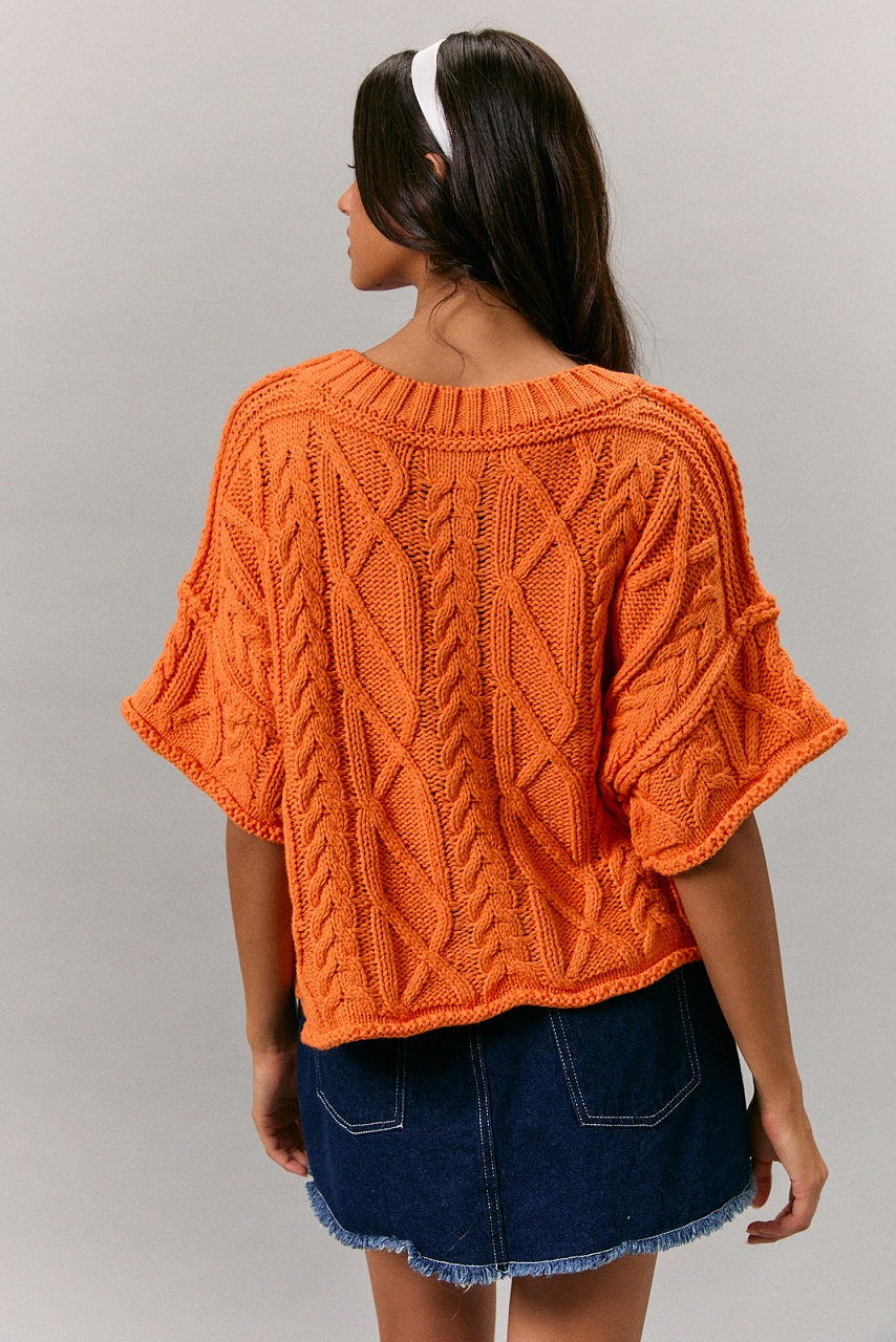 Bright orange boxy cable knit short sleeve sweater back view on model
