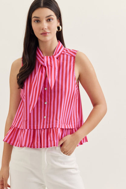 Woman wearing a pink and white striped sleeveless top with a tie detail on a plain background