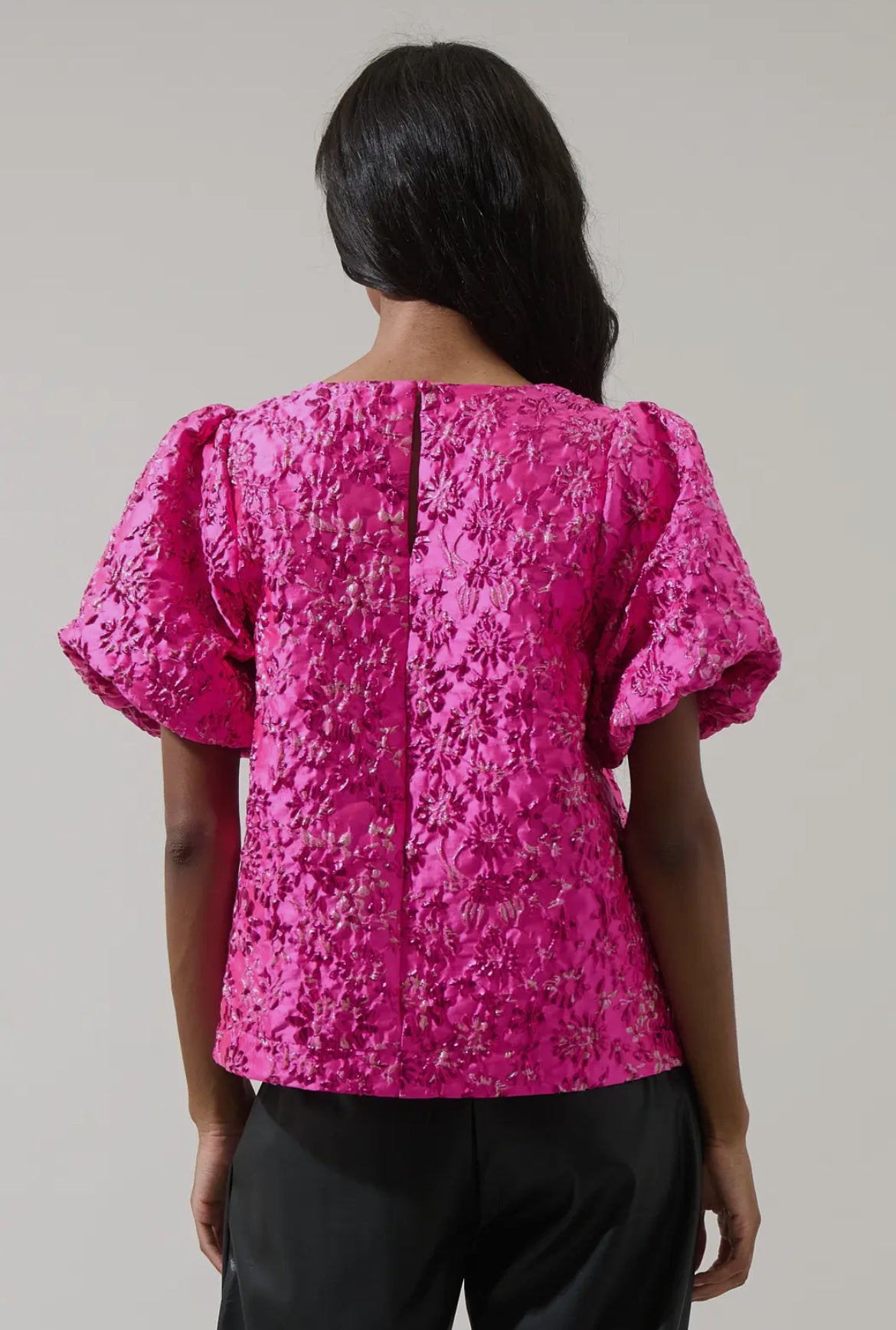 Back view of hot pink embroidered puff sleeve top featuring floral texture and hidden zipper — vibrant boutique blouse.
