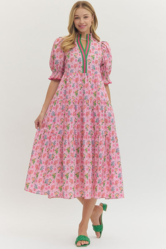 Woman wearing a pink floral dress with green accents on a white background