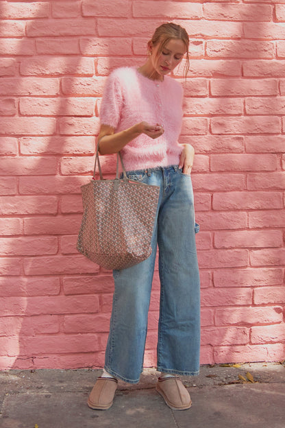 Pink pearl button fuzzy knit cardigan styled with jeans and tote bag against pink wall