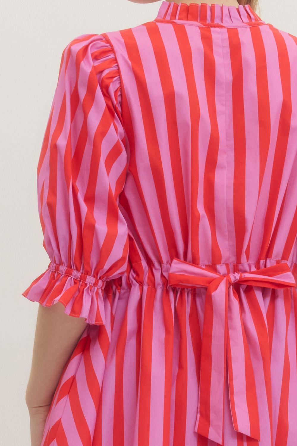 Red and pink striped dress with a bow detail on a plain background