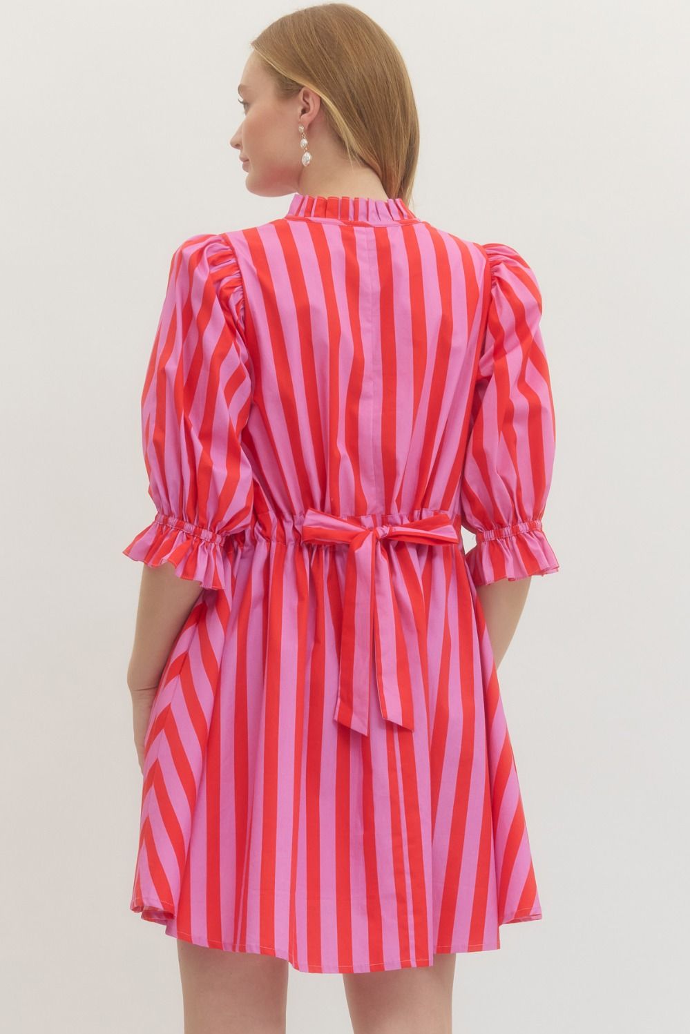 Woman wearing a red and pink striped dress with a white background