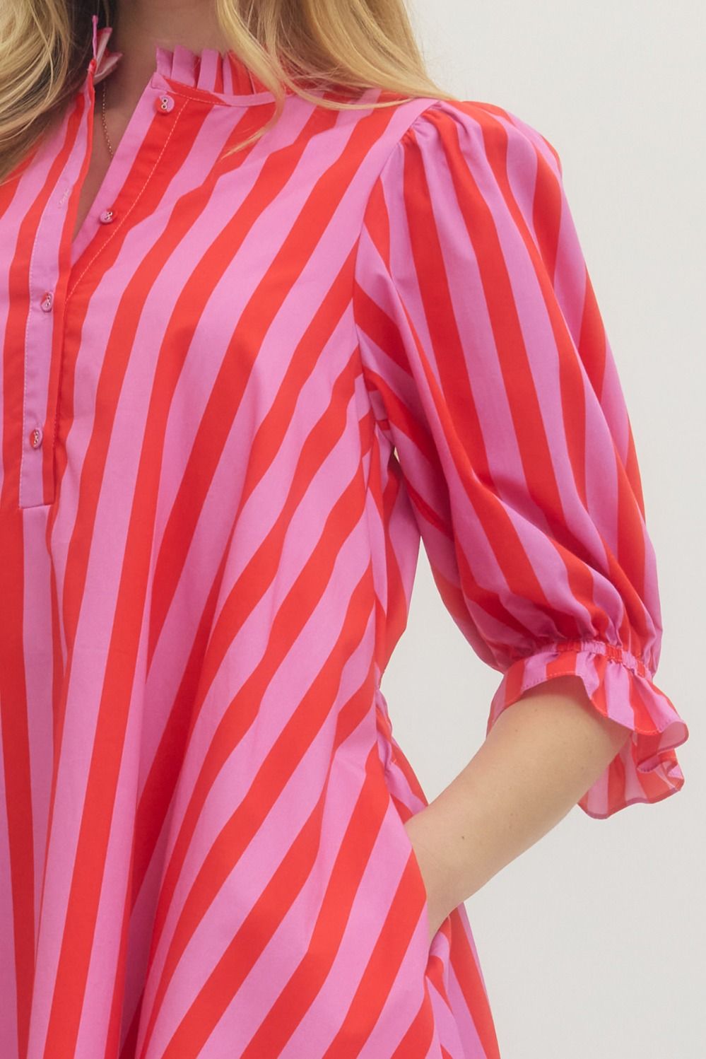 Red and pink striped shirt worn by a person on a white background