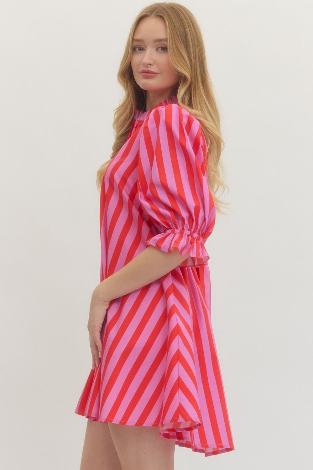 Woman wearing a pink and red striped dress against a plain background
