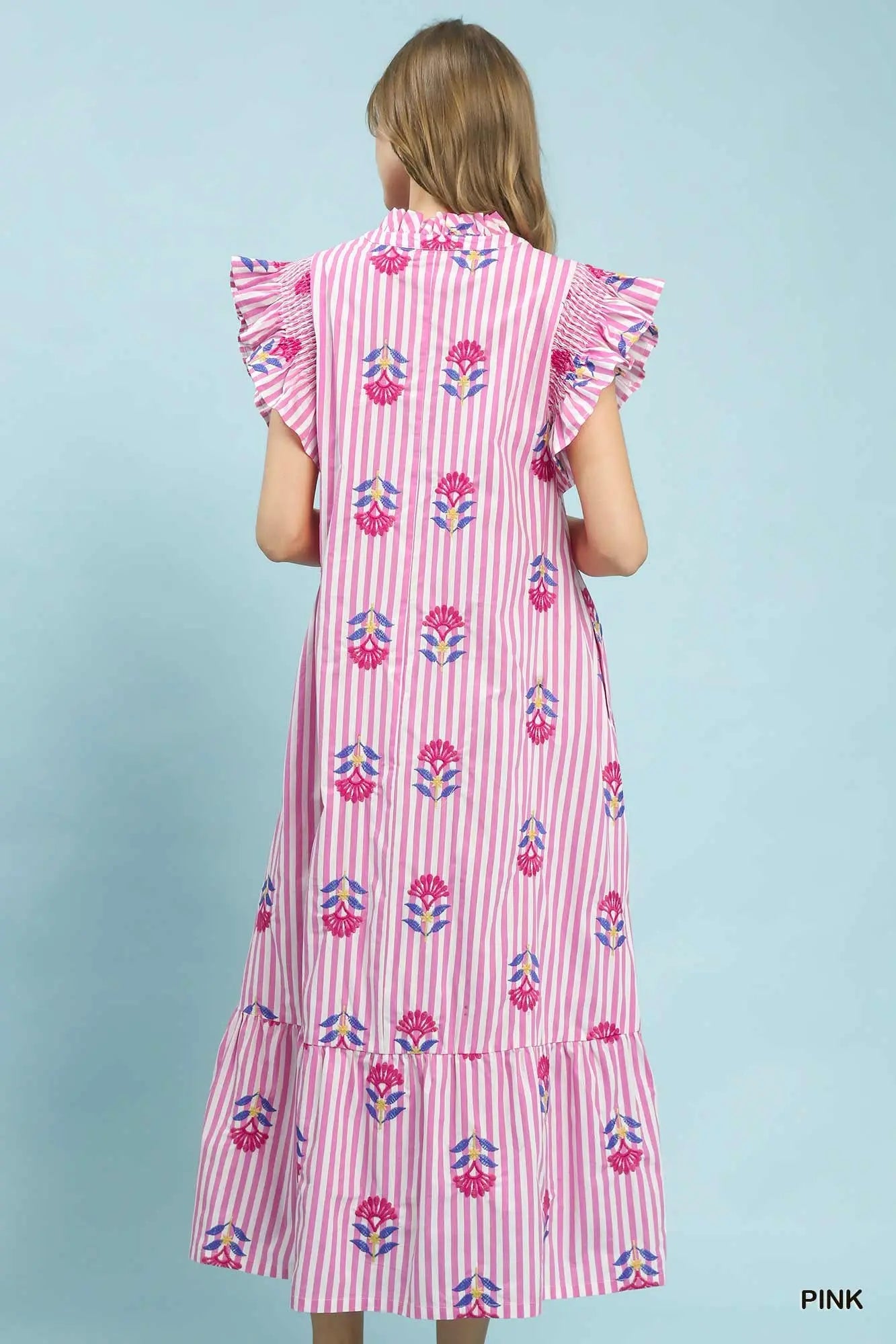 Woman wearing a pink dress with floral pattern on a light blue background