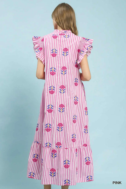 Woman wearing a pink dress with floral pattern on a light blue background