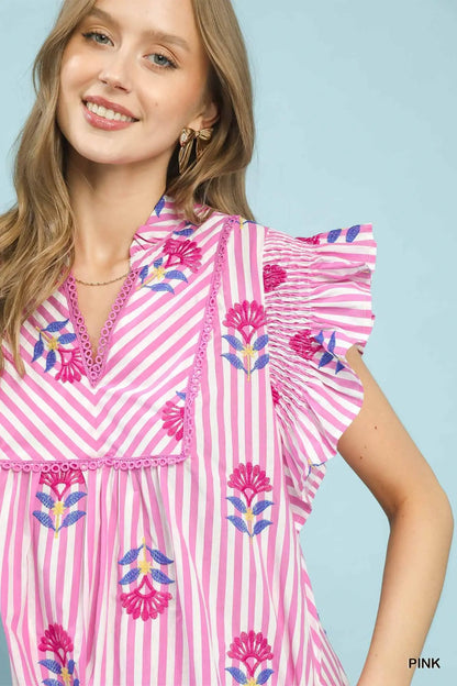 Woman wearing a pink dress with floral patterns on a light blue background