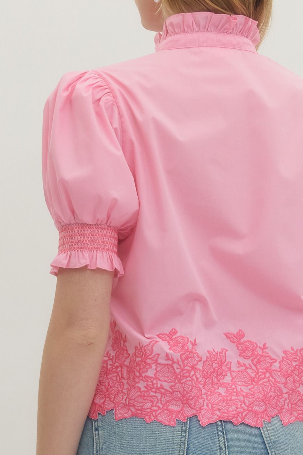Pink blouse with lace details on a plain background