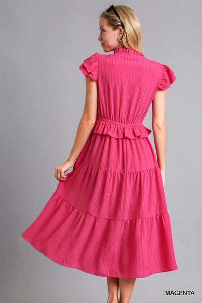Back view of The Pink Posh Midi Dress in vibrant magenta with flattering elastic waistband and layered tiers.